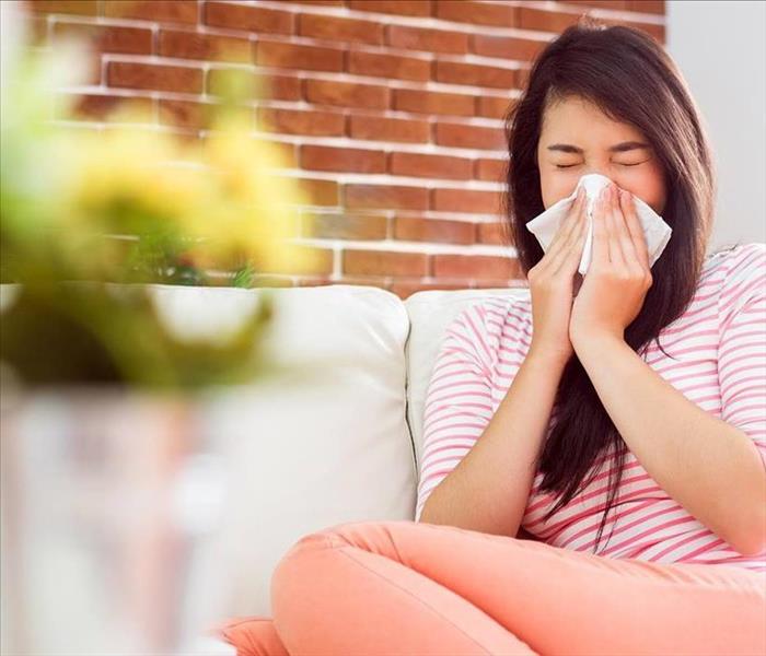 Women suffering from allergies blowing her nose